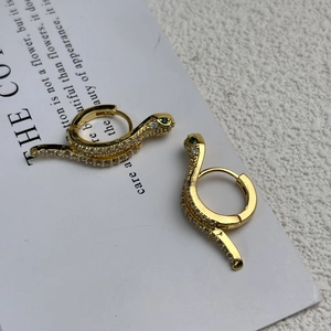 Detailed macro shot of 18K gold plated snake hoop earrings with green zircon eyes