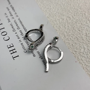Macro shot of silver snake earrings with green gemstones and white cubic zirconia