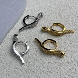 Gold and silver serpent hoop earrings with sparkling pave stones and green gem eyes