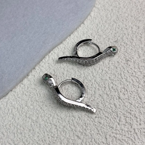 Detailed close-up of snake earrings with white cubic zirconia and green zircon eyes