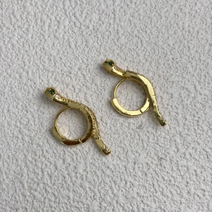 Detail of snake hoop earrings in 18K gold plating with green stones and white crystals