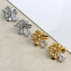 Macro detail of elegant flower stud earrings with pear-cut zircon in gold and silver