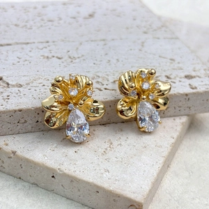 Macro view of gold flower earrings with sparkling zircons and pear-shaped drop stones