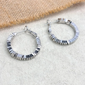 Detail view of silver geometric beaded hoop earrings with industrial square block design