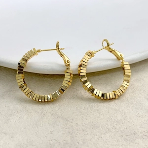 Detailed close-up of gold-plated square bead hoop earrings on white ceramic surface