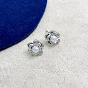 Macro detail of camellia flower stud earrings with silver petals and pearl centers