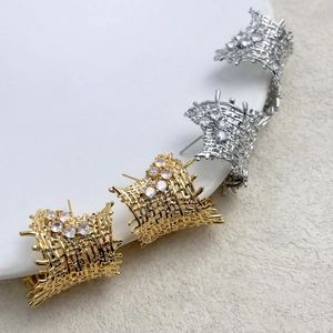 Detail of woven mesh earrings in gold and silver finish with sparkling zircons