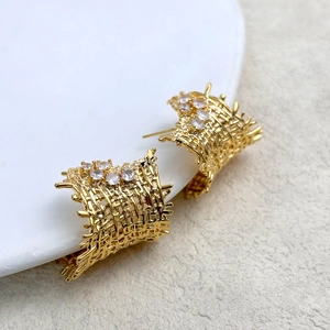Macro shot of gold-plated woven mesh stud earrings with sparkling zircon accents
