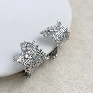 Detail of silver woven mesh stud earrings with sparkling cubic zirconia on ceramic plate