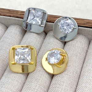 Detail of square and round zircon stud earrings in gold and silver plating on fabric