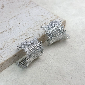 Detailed macro view of silver mesh earrings with woven pattern and sparkling zircons