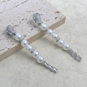 Macro view of long tassel earrings with white pearls and sparkling zircon drops
