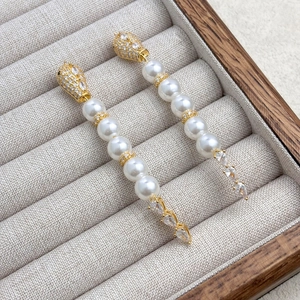 Detailed close-up of snake-style tassel earrings with white pearls and drop zircons