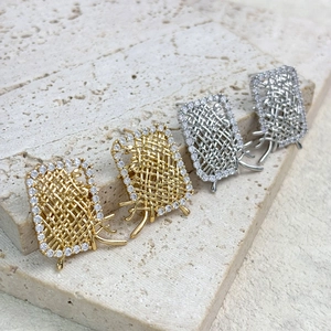 Gold and silver woven metal geometric earrings with crystal accents on stone background