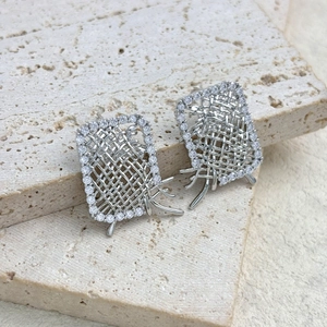 Macro shot of silver woven rectangular earrings with zircon border on stone base