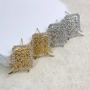 Macro shot of rectangular metal woven earrings with cubic zirconia edges in gold and silver