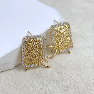 Detail of gold rectangular earrings featuring woven texture and cubic zirconia border