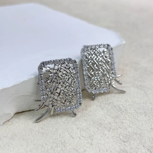 Silver woven rectangle earrings with crystal trim and branch detail on a stone pedestal