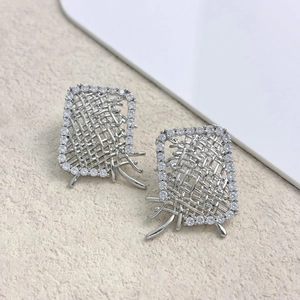 Macro shot of silver woven metal texture and pavé zircon square stud earrings