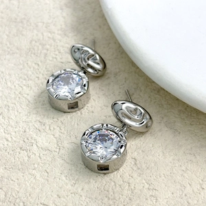 Detailed close-up of fluid texture earrings with large claw-set zircon and 18K gold plating