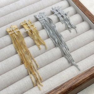 Détails des boucles d'oreilles pompons argentées et dorées ornées de strass brillants