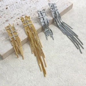 Boucles d'oreilles pendantes dorées et argentées serties de cristaux sur fond pierre