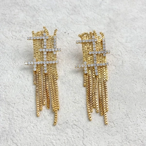 Détail de boucles d'oreilles à pompons dorés avec grille rectangulaire et cristaux brillants