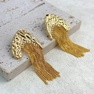 Gros plan de boucles d'oreilles vintage dorées à texture martelée et longues chaînes glands