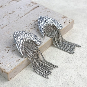 Gros plan sur les boucles d'oreilles à pompons argentés et texture martelée