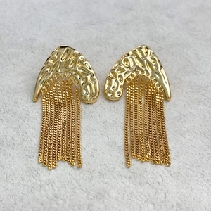 Gros plan de boucles d'oreilles dorées martelées avec de longues franges en chaîne
