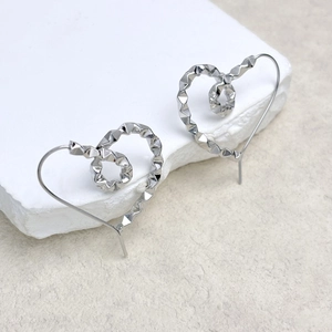 Macro shot of silver heart earrings featuring geometric faceted textures on stone