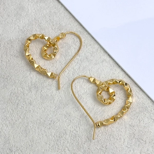 Detailed view of gold heart stud earrings with geometric 3D faceted texture