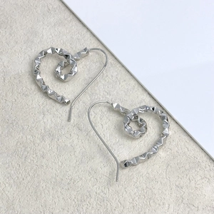 Detail shot of silver heart spiral drop earrings with multifaceted metallic texture