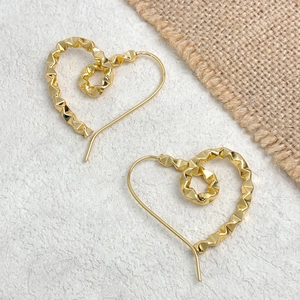 Detailed view of gold heart earrings with geometric faceted texture on stone background