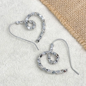 Macro shot of silver twisted heart earrings with studded texture and metallic finish