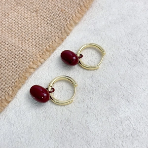 Boucles d'oreilles créoles rétro bordeaux et or avec pendentifs lisses sur fond blanc