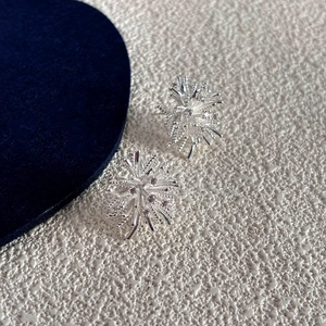 Detailed close-up of snowflake stud earrings with sparkling crystals on blue velvet
