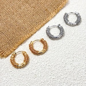 Detail of gold and silver wire-wrapped hoop earrings on a textured background
