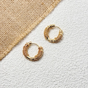 Macro detail of French style 18K gold plated hoop earrings with irregular wire wrap design
