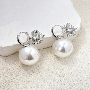 Élégantes boucles d'oreilles perles avec nœud doré et zircon sur un anneau sophistiqué