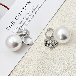 Détail de boucles d'oreilles nœud en perles dorées avec zircons en forme de cœur