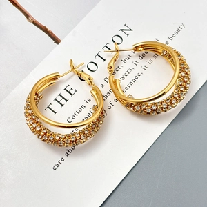Détail de boucles d'oreilles doubles anneaux dorés avec incrustation de zircons