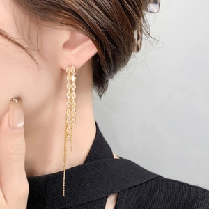 Close-up of golden tassel earrings with marquise-cut stones worn by a model