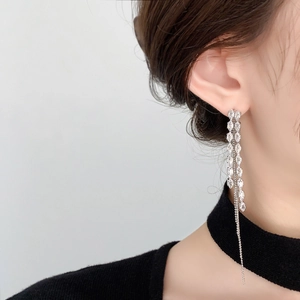 Close-up of long silver tassel earrings with marquise-cut crystals on a model