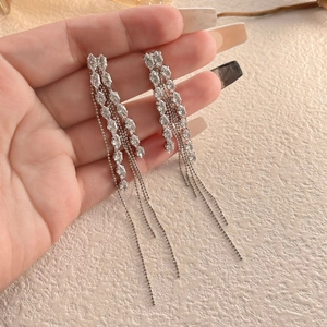 Long silver tassel earrings with marquise cut stones held by hand showing drape