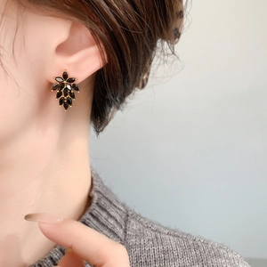 Primo piano di orecchini di zircone nero a forma di foglia su una modella in oro
