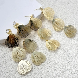 Three pairs of gold layered leaf drop earrings with round zircon studs on white stone pedestals