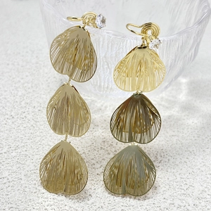 Detail of gold petal clip-on earrings with heart hollow design and zircon stone