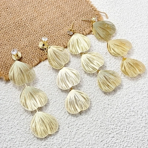 Detailed view of long gold textured heart earrings featuring sparkling zircon accents