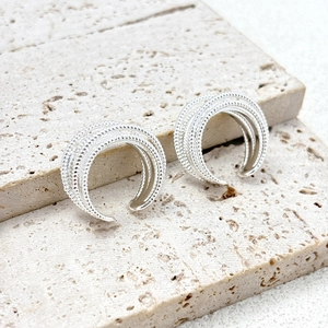 Macro detail of silver multi-layered C-shaped earrings with beaded texture on stone